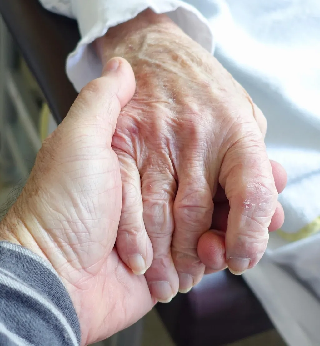 Jüngere Hand hält die Hand eines pflegebedürftigen älteren Menschen – Gute Besserung – Sprüche für kranke Menschen