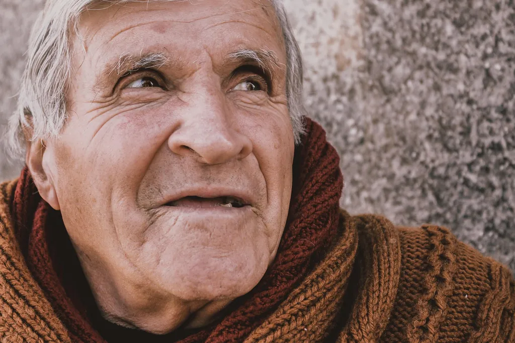 Älterer Mann mit warmem Blick im Strickpullover – Sprüche für Opa – die schönsten Glückwünsche