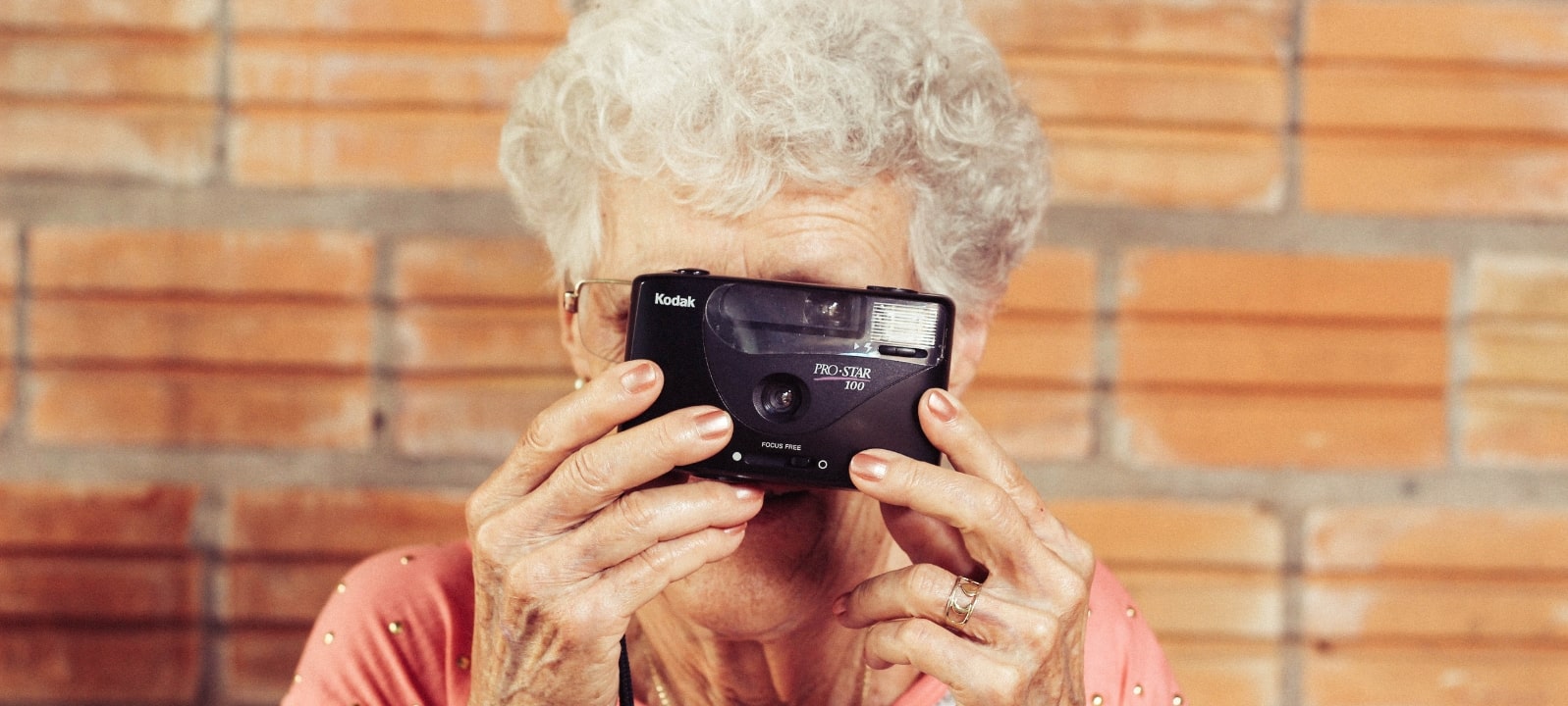 Eine Rentnerin lacht und hat ein Fotoapparat vor dem Gesicht.